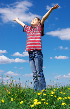 A child stands in a field with arms outstretched to greet the sun. Catholic Charities Maine offers innovative social services in support of communities throughout the state.