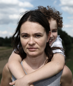 A woman carries a child piggyback in an outdoor setting. Catholic Charities Maine provides assistance for individuals and families in need, no matter what their faith or ability to pay